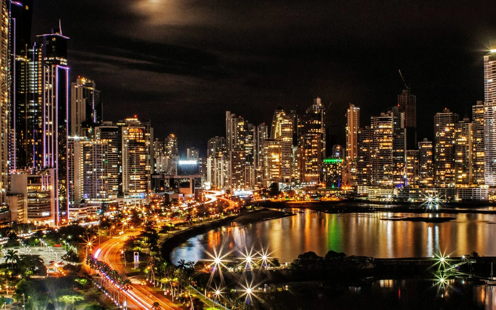 Die beleuchtete Skyline von Panama City bei Nacht, gespiegelt in der Bucht.