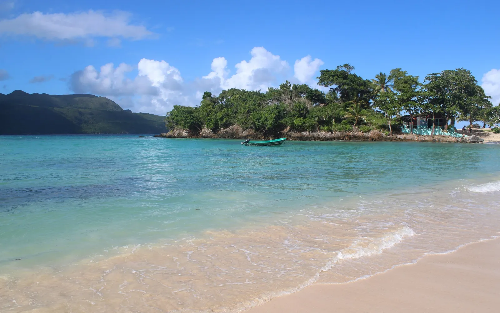 Türkises Wasser und eine bewaldete Insel vor grünen Hügeln an der Küste von Samaná.