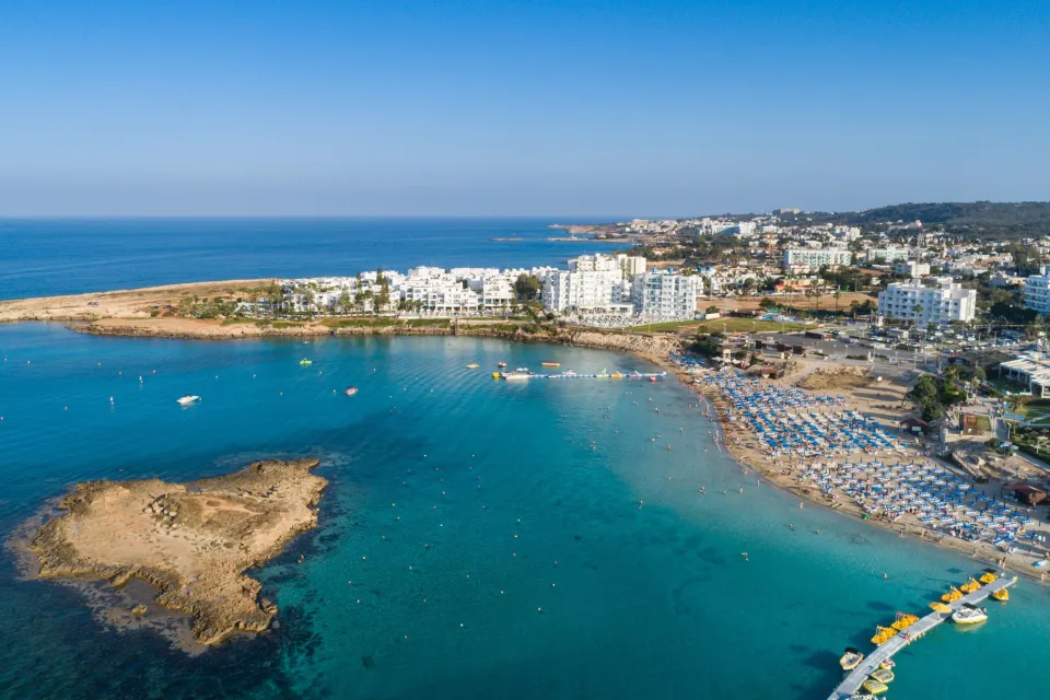 Luftaufnahme der Fig Tree Bay bei Protaras mit türkisem Wasser und kleiner Insel.