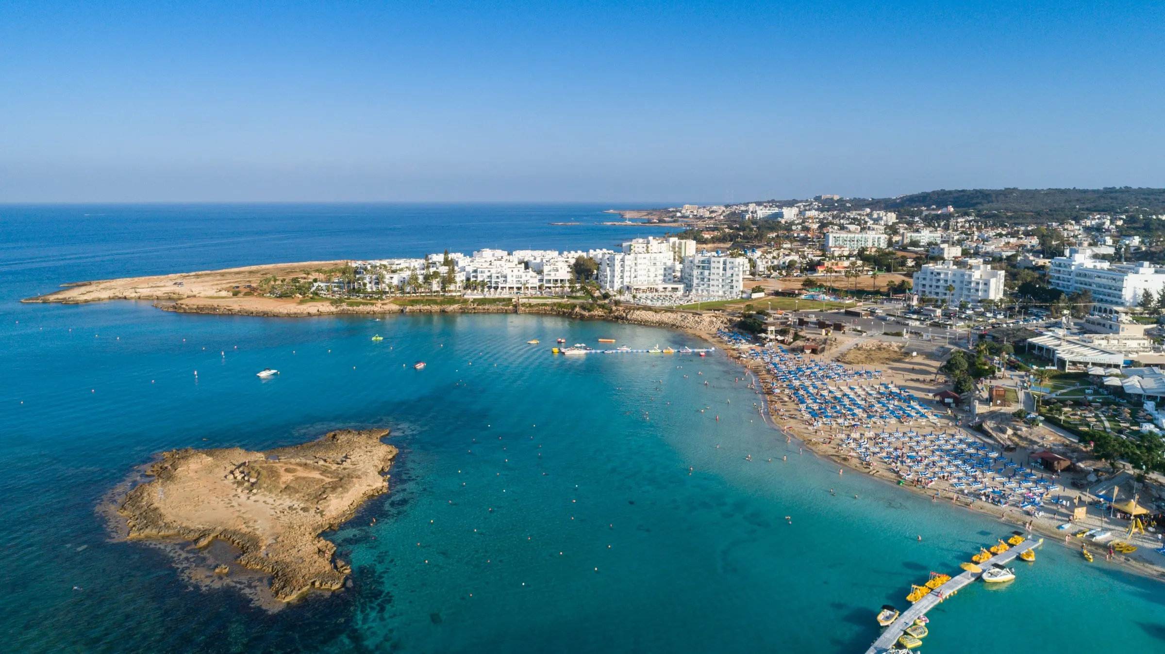 Luftaufnahme der Fig Tree Bay bei Protaras mit türkisem Wasser und kleiner Insel.