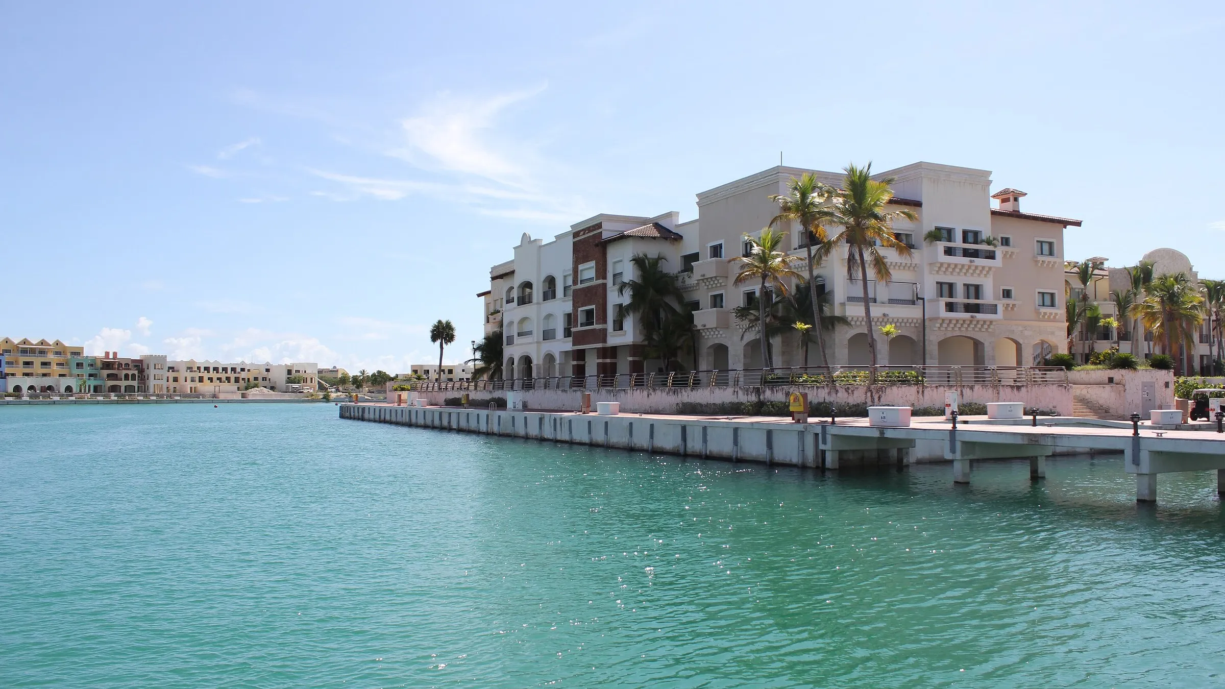 Die Marina von Cap Cana mit Booten, Steg und Wohngebäuden am Wasser.