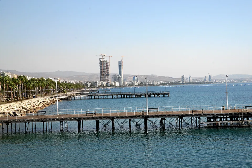 Holzstege an der Strandpromenade von Limassol mit der Skyline im Hintergrund.