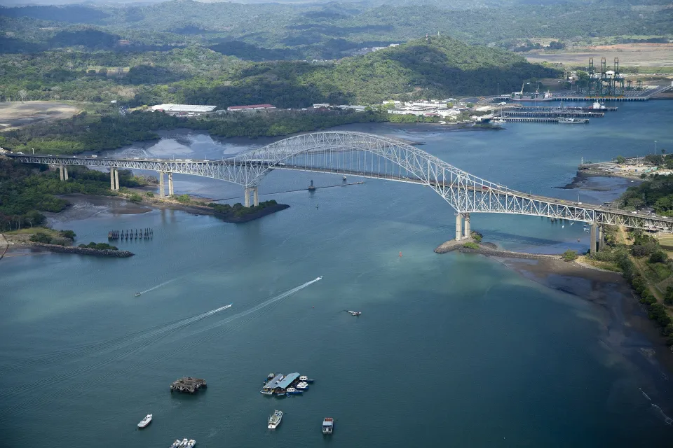 Luftaufnahme der Puente de las Américas über die Kanaleinfahrt, mit grünen Hügeln auf der Westseite.